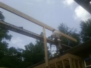 Carpenter setting a ridge beam over a new addition frame in Roxbury