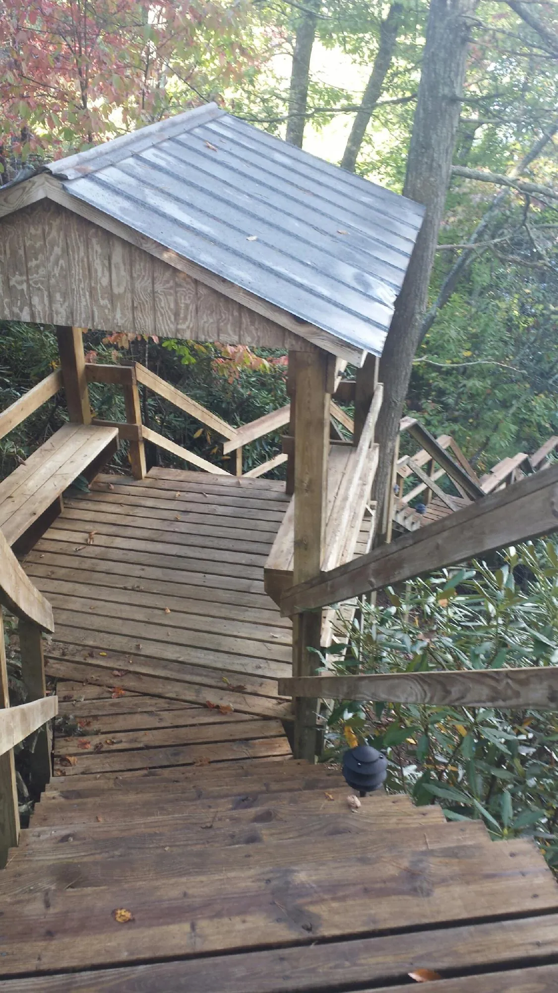 Metal roofed shelter over wooden steps on a wooded walkway — Skylight Repair & Installation work by our crew in Roxbury