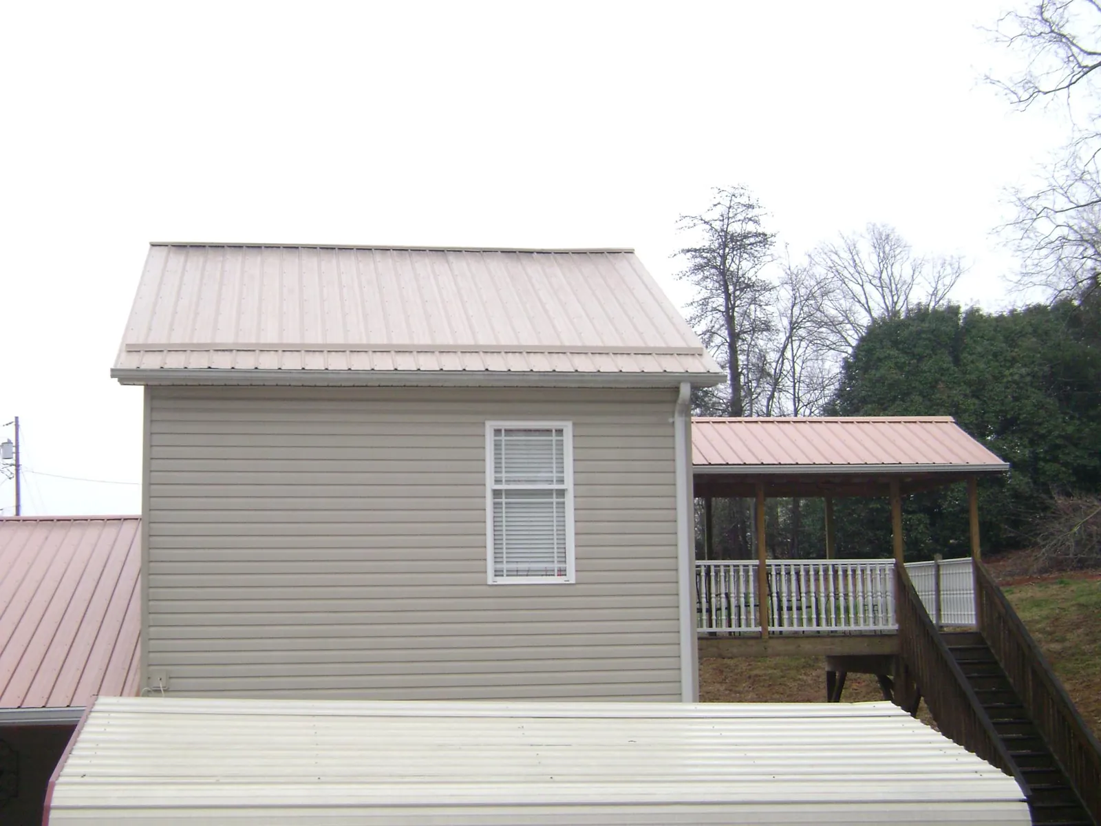 Tan metal roofs on a two story addition and attached porch, from a Roof Replacement job in Roxbury